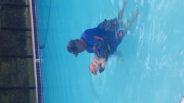 Counselor teaching child to swim in pool