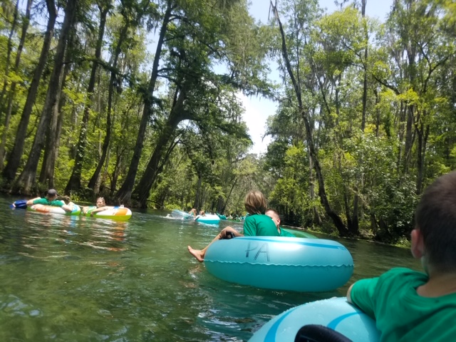 Campers tubing down a shady river