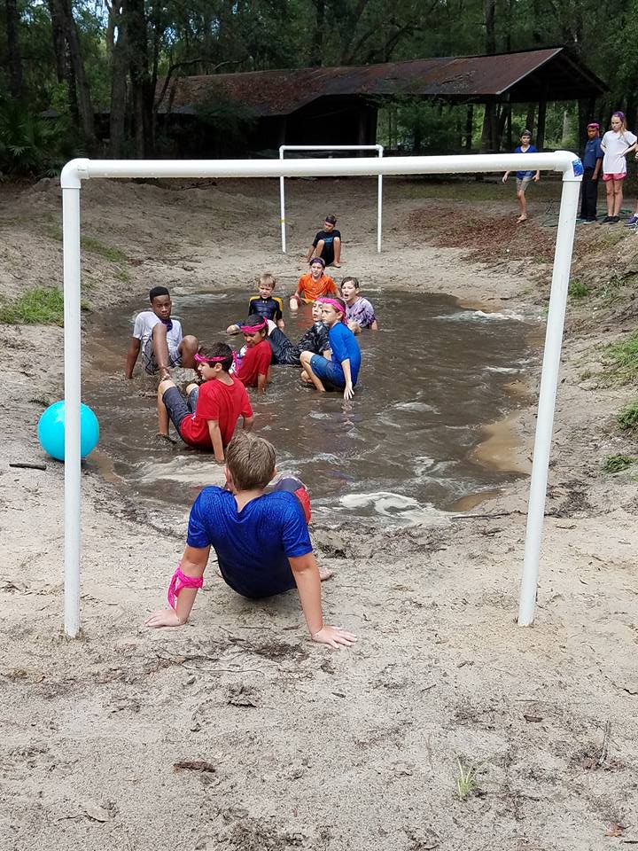 Campers splashing through muddy water pit