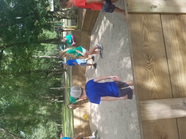 Kids playing gaga ball in sandy wooden pit